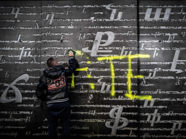 A man cleans an outside wall of the National Armenian Memorial Centre in Decines-Charpieu, near Lyon, on November 1, 2020 where pro-Turkish yellow letters graffiti tags have been painted overnight. - Inscriptions read "RTE" which can refers to Turkish Prime minister Recep Tayyip Erdogan and "Grey Wolf" (Loup Gris), the …