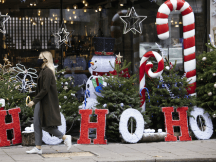 LONDON, ENGLAND - NOVEMBER 23: A woman wearing a facemask walks past Christmas decorations