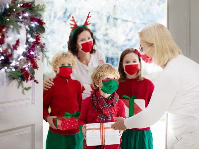 Family with child at grandmother on Christmas day in covid-19 outbreak. Kids in face mask