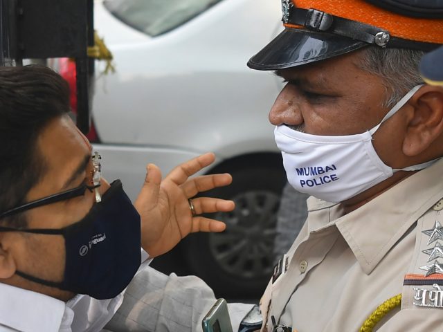 A supporter of Bharatiya Janata Party (BJP) is stopped by a policeman while protesting aga