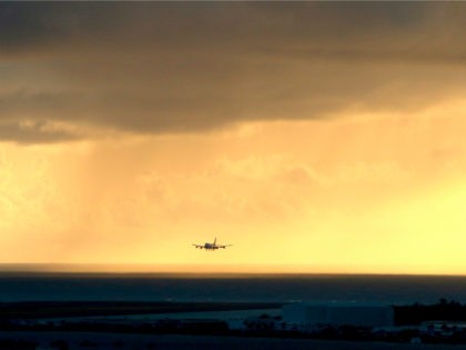 A plane lands as the sun sets over the international airport in Honolulu on Monday, April 6, 2020. (AP Photo/Caleb Jones)