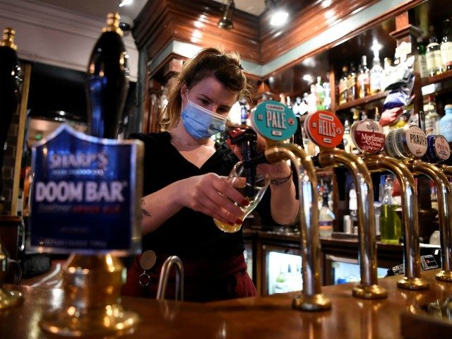 A server wearing a face mask or covering due to the COVID-19 pandemic, pours a pint of Camden Pale Ale inside a pub in Mayfair, London on November 3, 2020, as the country prepares for a second national lockdown during the novel coronavirus COVID-19 pandemic. - English pubs call last …