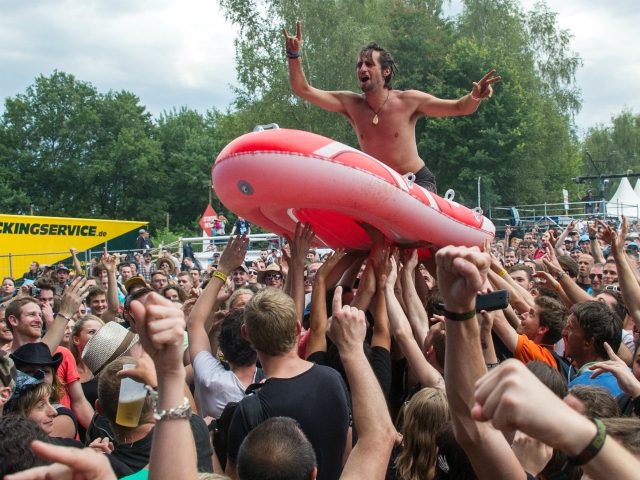 A man on a plastic boat is carried by festival-goers - also known as "crowd-surfing&q