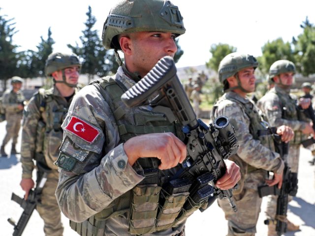 Turkish soldiers stand before people demonstrating as they secure a section of the M4 high