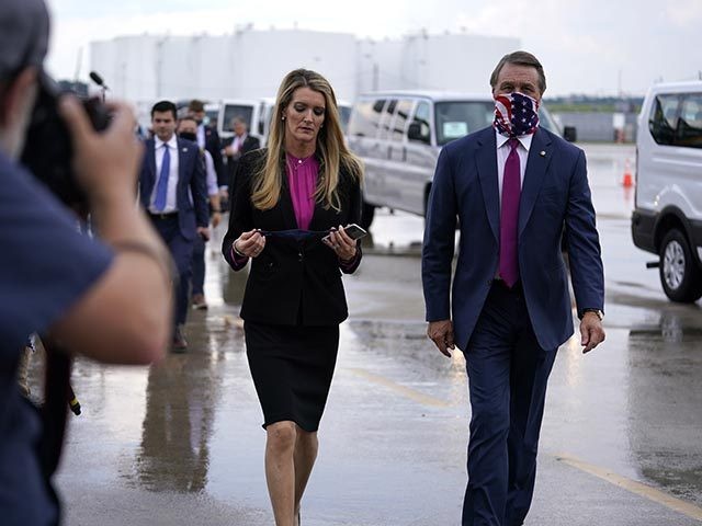 Sen. Kelly Loeffler, R-Ga., puts on a face mask as she walks with Sen. David Perdue, R-Ga., right, at UPS Hapeville Airport Hub, Wednesday, July 15, 2020, in Atlanta. (AP Photo/Evan Vucci)