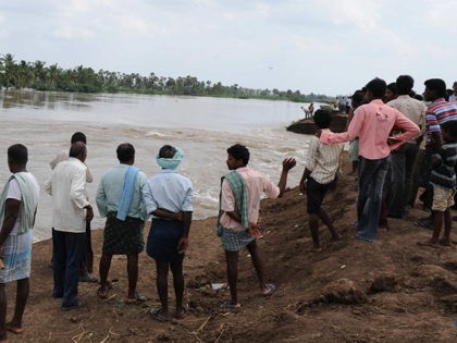 Indian villagers stand on the banks of a flooded river in Oleru village of Guntur district some 400 km from Hyderabad on October 6, 2009. Aid workers used helicopters and boats to try to reach survivors of massive floods in southern India that have killed at least 280 people, as …
