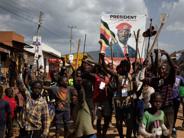 MBALE, UGANDA - DECEMBER 29: People parade with a Bobi Wine poster during a circumcision ceremony on December 29, 2020 in Mbale, Uganda. Bobi Wine is taking on incumbent president Yoweri Museveni on the January 14 2021 election. Imbalu is a biannual community tradition of the Bagisu tribe in eastern …