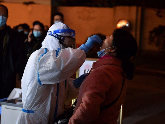 This photo taken on December 8, 2020 shows a health worker conducting a nucleic acid test on a resident in Chengdu, in western China's Sichuan province, after new Covid-19 coronavirus cases were detected in the city. (Photo by STR / AFP) / China OUT (Photo by STR/AFP via Getty Images)