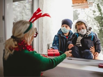 Children bring their grandmother a Christmas present at the window. Holidays during epidemic. - stock photo