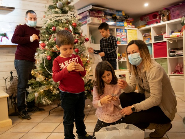 Maurizio Di Giacobbe, left, and Glenda Grossi, right, place decorations on a Christmas tree, with their children from left, Tiziano, 4, Arianna, 9, and Flavio 10, in their house in the outskirts of Rome, Saturday Dec. 12, 2020. The coronavirus pandemic has posed unprecedented challenges for families around the world managing work and home life with children kept home from school and after-school activities. For the Di Giacobbe family, the juggling is even more complicated since mom and dad are intensive care nurses in the same COVID-19 ward and spend their days tag-teaming shifts, trying to give their patients the level of personal care and attention they would give their own children. (AP Photo/Alessandra Tarantino)
