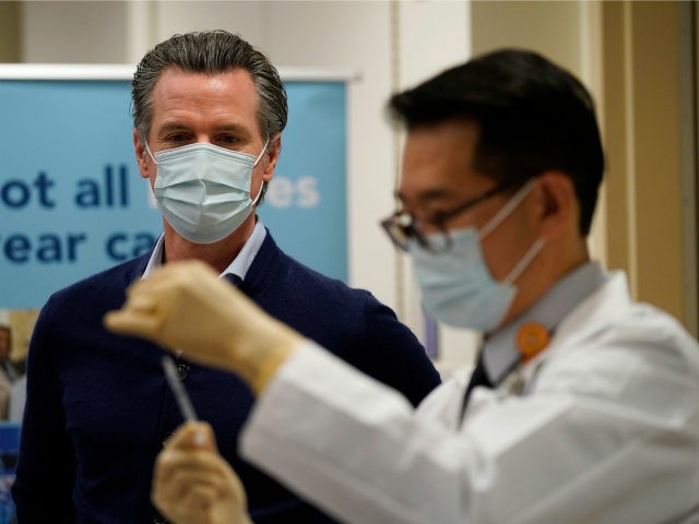 Governor Gavin Newsom watches as the Pfizer-BioNTech COVID-19 vaccine is prepared by Direc