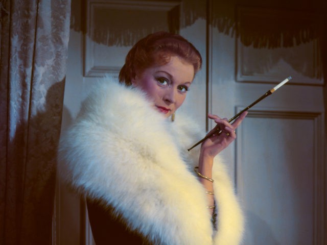 A model wearing a fur coat and smoking using a cigarette holder, circa 1950. (Photo by Hu