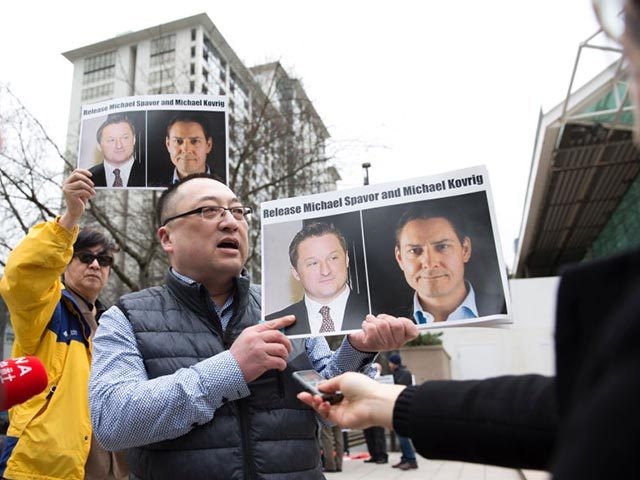 Louis Huang of Vancouver Freedom and Democracy for China holds photos of Canadians Michael Spavor and Michael Kovrig, who are being detained by China, outside British Columbia Supreme Court, in Vancouver, on March 6, 2019, as Huawei Chief Financial Officer Meng Wanzhou appears in court. - Meng Wanzhou, the Chinese …