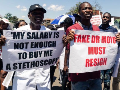 Doctors hold banners during a protest march by senior medical doctors in Harare, on December 4, 2019. - The doctors petitioned the Zimbabwe Parliament demanding improved working conditions and the reinstatement of 448 junior doctors fired for taking part in a two month long strike over low salaries. (Photo by …