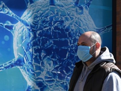 TOPSHOT - A man wearing a mask walks past the Regional Science Centre in Oldham, Lancashire on March 26, 2020, during a country-wide lockdown to slow the spread of the novel coronavirus COVID-19. (Photo by Oli SCARFF / AFP) (Photo by OLI SCARFF/AFP via Getty Images)