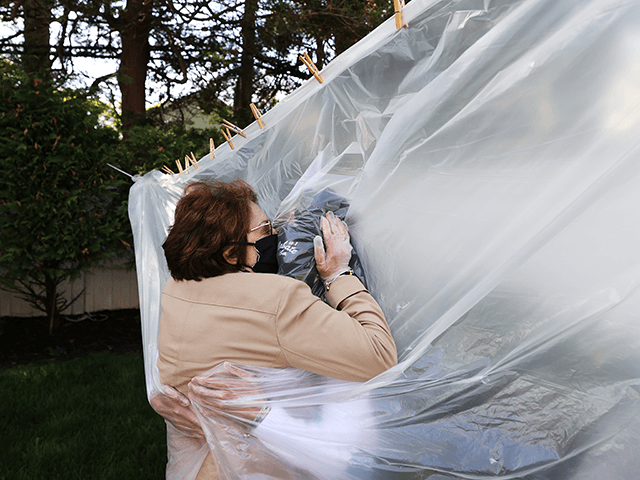 Michelle Grant (R) hugs her mother, Mary Grace Sileo through a plastic drop cloth hung up on a homemade clothes line during Memorial Day Weekend on May 24, 2020 in Wantagh, New York. It is the first time they have had physical contact of any kind since the coronavirus COVID-19 …