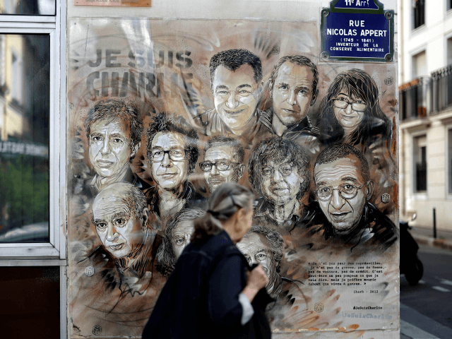 TOPSHOT - A woman walks past a painting by French street artist and painter Christian Guemy, known as C215, in tribute to members of Charlie Hebdo newspaper who were killed by jihadist gunmen in January 2015, in Paris, on August 31, 2020. - Fourteen alleged accomplices in the 2015 jihadist …