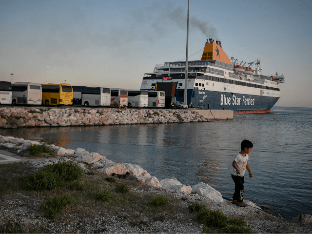 A child plays by the sea as hundreds of refugees from the islands of Lesbos, Chios, Samos, Kos and Leros wait to board buses after disembarking at the port of Lavrio, some 70 km south-east of Athens, prior to be transferred to camps in mainland Greece, on September 29, 2020. …