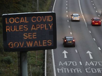 Traffic passes a COVID-19 sign displayed along the M4 motorway in southeast Wales on Octob