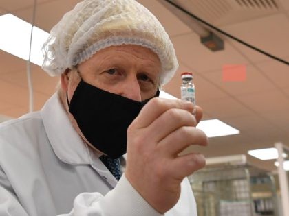 Britain's Prime Minister Boris Johnson, wearing a hair net and face covering, poses for a photograph with a vial as he views the last minute quality testing of the 'fill and finish' stage of the manufacturing process of COVID-19 vaccines, during his visit to Wockhardt's pharmaceutical manufacturing facility in Wrexham, …