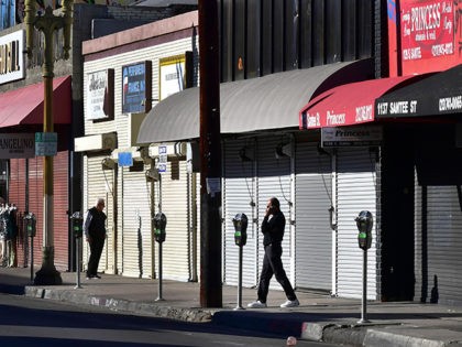 A man speaks on his cellphone in front of a row of shuttered small businesses in Los Angeles, California on November 30, 2020. - Los Angeles County's new stay-at-home restrictions took effect on November 30, 2020, one day after the county reported more than 5,000 new COVID-19 cases. (Photo by …