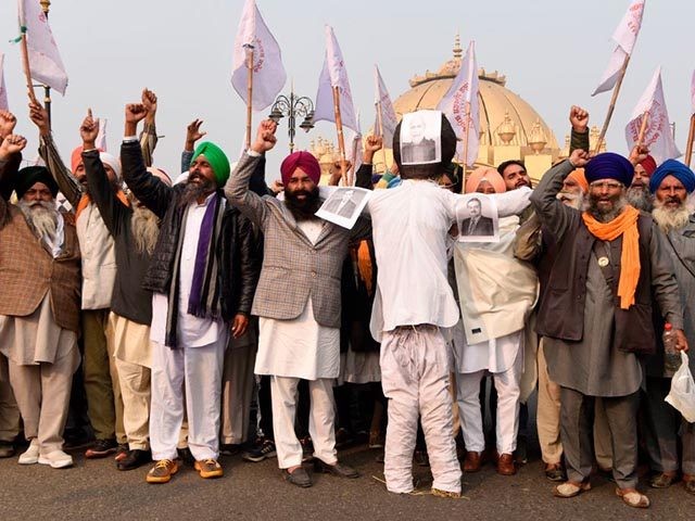 Farmers shout slogans before burning an effigy of India's Prime Minister Narendra Modi (C) , Chairman of Reliance Industries Ltd company Mukesh Ambani (L) and Chairman and Founder of the Adani Group Gautam Adani (R) to protest against corporate businesses following the recent passing of agriculture bills in Parliament, in …