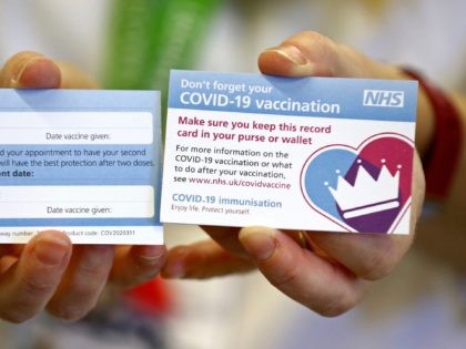 A model holds a card which will be given to patients following their vaccination for COVID
