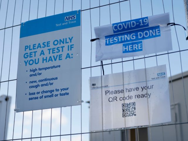 A sign is pictured on a fence outside a novel coronavirus COVID-19 walk-in testing centre in Walthamstow in north east London, on December 15, 2020. - Two leading British medical journals urged the government Tuesday to scrap plans to ease coronavirus restrictions over Christmas, warning it would be "another major …