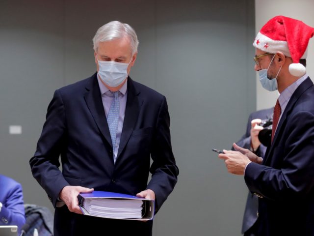 EU Chief Negotiator for Brexit Michel Barnier (L) is watched by a Greek representative, while carrying a folder containing the 2000 page 'Brexit Trade Deal' as he arrives ahead of a special meeting of The Committee of the Permanent Representatives of the Governments of the Member States to the European …