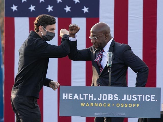 STONECREST, GA - DECEMBER 28: Georgia Democratic Senate candidates Raphael Warnock (R) and Jon Ossoff (L) bump elbows during a "It's Time to Vote" drive-in rally on December 28, 2020 in Stonecrest, Georgia. With a week until the January 5th runoff election that will determine control of the Senate, candidates …