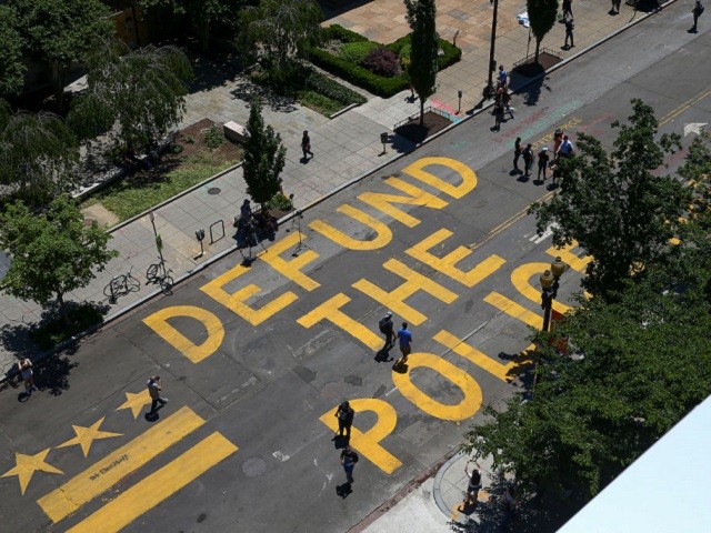 People walk down 16th street after “Defund The Police” was painted on the street near the White House on June 08, 2020 in Washington, DC. After days of protests in DC over the death of George Floyd, DC Mayor Muriel Bowser renamed that section of 16th street "Black Lives Matter Plaza". (Tasos Katopodis/Getty Images)