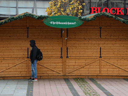 A man stands in front of a closed christmas tree decorations stall at the cancelled annual