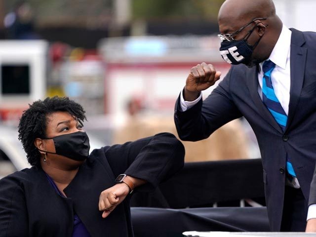 ATLANTA, GA - DECEMBER 15: U.S. Democratic Senate candidate Raphael Warnock (R) bumps elbows with Stacey Abrams (L) during a campaign rally with U.S. President-elect Joe Biden at Pullman Yard on December 15, 2020 in Atlanta, Georgia. Biden’s stop in Georgia comes less than a month before the January 5 …