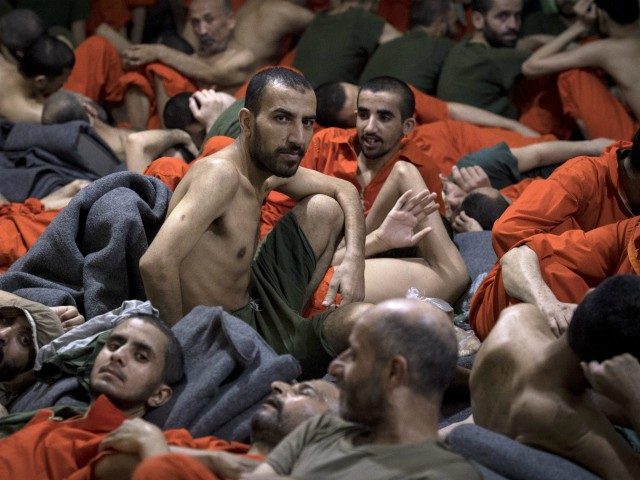 Men, accused of being affiliated with the Islamic State (IS) group, sit on the floor in a prison in the northeastern Syrian city of Hasakeh on October 26, 2019. - Kurdish sources say around 12,000 IS fighters including Syrians, Iraqis as well as foreigners from 54 countries are being held …