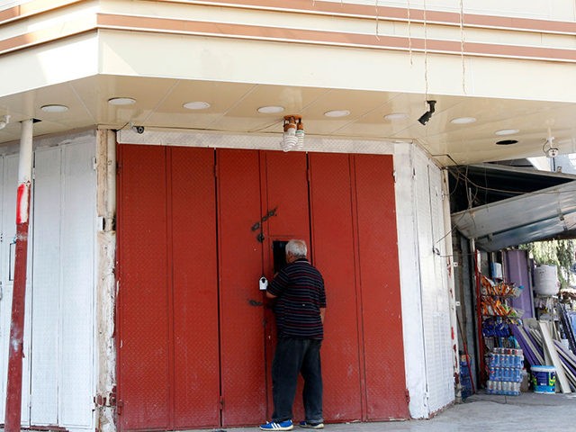 An Iraqi man buys liquor from a closed shop, that is selling illegaly through a window, in