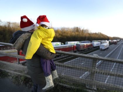 A mother and child look at the line of trucks parked up on the M20, part of Operation Stack in Ashford, Kent, England, Friday, Dec. 25, 2020. Thousands wait to resume their journey across The Channel after the borders with France reopened. Trucks inched slowly past checkpoints in Dover and …