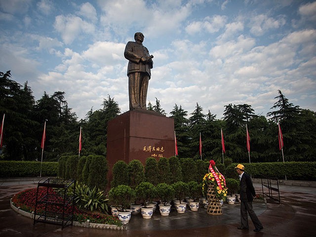 This picture taken on April 21, 2016 in Shaoshan shows a Chinese tourist in front of a huge bronze Mao statue. Shaoshan in central China's province Hunan is the hometown of former communist leader Mao Zedong. The small village is a hotspot for 'red tourism'. Millions of Mao devotees from …