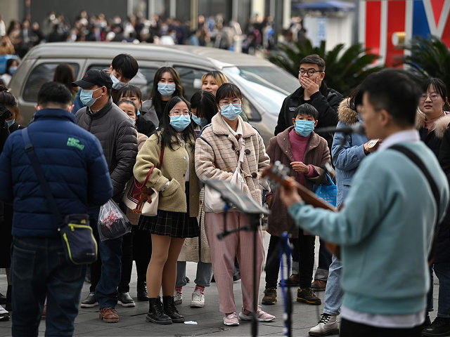 People wearing face masks listen to a performer at a shopping centre in Chengdu, the capital of southwest Sichuan province, on November 28, 2020. (Photo by Noel Celis / AFP) (Photo by NOEL CELIS/AFP via Getty Images)