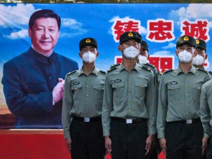 Soldiers of the People's Liberation Army's Honour Guard Battalion wear protective masks as they stand at attention in front of photo of China's president Xi Jinping at their barracks outside the Forbidden City, near Tiananmen Square, on May 20, 2020 in Beijing, China. China's government will open its annual weeklong …