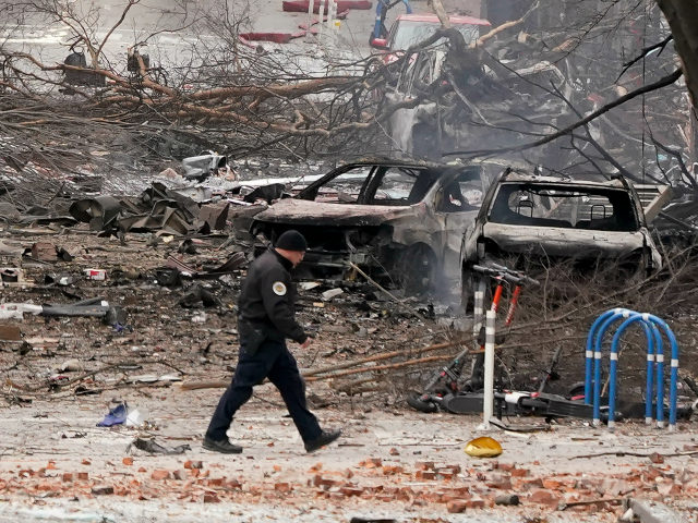 A law enforcement member walks past damage from an explosion in downtown Nashville, Tenn.,