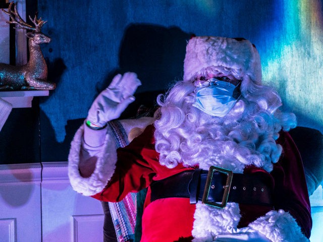 A person dressed as Santa waves to passing cars at Starlight Lane, a drive-through Christm