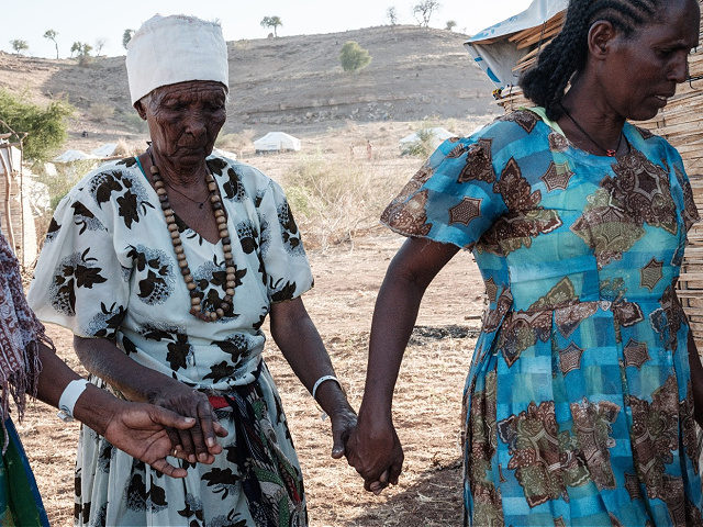 Ethiopian Asafu Alamaya (C), a 80-year-old blind who fled the Tigray conflict, is guided b