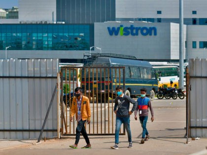 People exit from the gate of Wistron, a Taiwanese-run iPhone factory at Narsapura, about 60 km from Bangalore on December 13, 2020. - Authorities vowed to crack down on workers who went on a violent rampage at a Taiwanese-run iPhone factory in southern India over allegations of unpaid wages and …