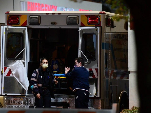 Paramedics wearing facemasks work behind an ambulance at the Garfield Medical Center in Mo