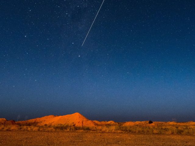 A long exposure shows the light trail of a re-entry capsule, carrying samples collected from a distant asteroid after being released by Japanese space probe Hayabusa-2, entering the Earth's atmosphere as seen from Coober Pedy in South Australia early on December 6, 2020. (Photo by Morgan Sette / AFP) (Photo …
