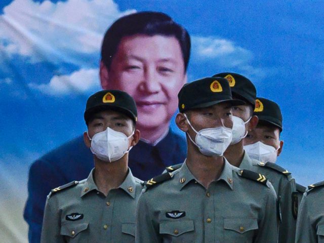 EIJING, CHINA - MAY 20: Soldiers of the People's Liberation Army's Honour Guard Battalion wear protective masks as they stand at attention in front of photo of China's president Xi Jinping at their barracks outside the Forbidden City, near Tiananmen Square, on May 20, 2020 in Beijing, China. China's government …