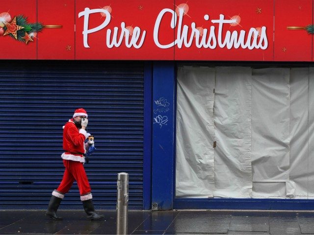 A man dressed as Santa Claus walks past a closed Christmas shop in central Glasgow ahead of the introduction of further coronavirus restrictions on November 20, 2020. - Swathes of western and central Scotland prepared to enter a three-week period of restrictions this evening. From 6:00 pm (1800 GMT) non-essential …