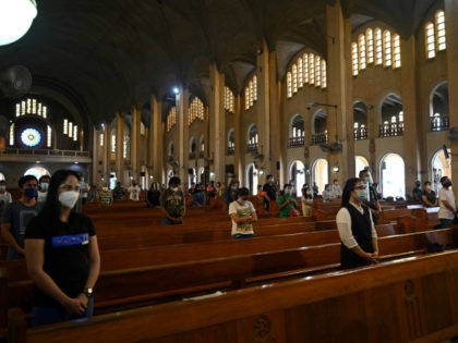 Catholic faithful wearing face shields and maintaining physical distancing attend a mass a