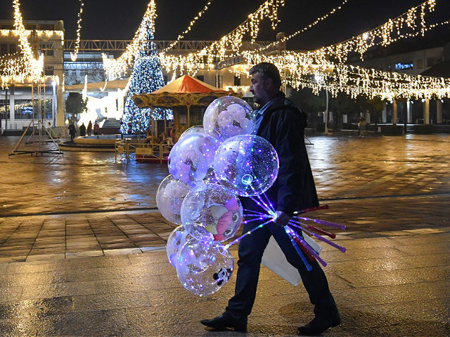 A man walks holding baloons on an almost deserted Podgorica's central square on New Year's