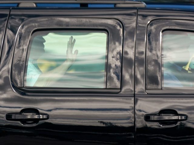 President Donald Trump waves as he rides in a motorcade vehicle while departing Trump Inte